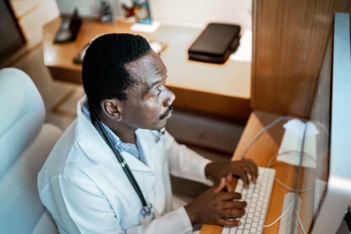 Focused mature doctor working using computer at the hospital
